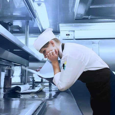 Sous Chef Köchin an Bord der Mein Schiff beugt sich in der Küche über den Menüplan