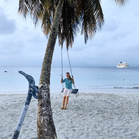 Crewmitglied von Phoenix Reisen am Strand in der Karibik auf Schaukel vor dem Schiff