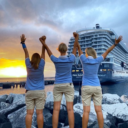 Drei Mein Schiff Crew Mitglieder bei Sonnenuntergang Arme nach Oben vor Mein Schiff 2