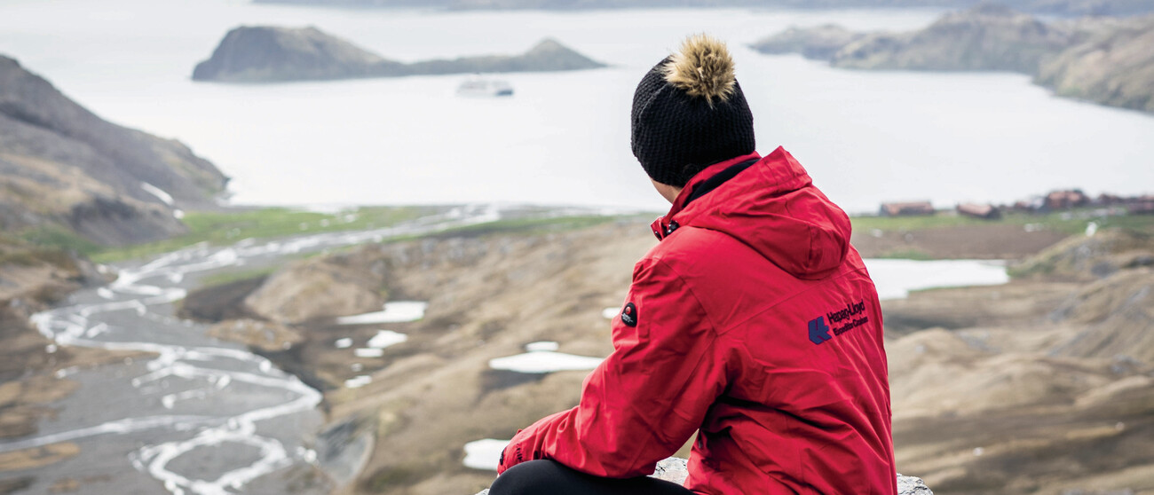 Crew-Mitglied von hinten mit Blick über eine Arktislandschaft auf die Hanseatic nature
