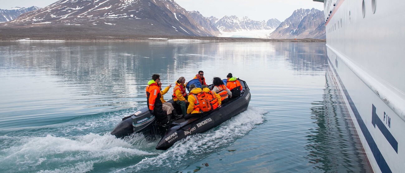 Expedition Guide fährt Gäste mit einem Zodiac durch die Arktis
