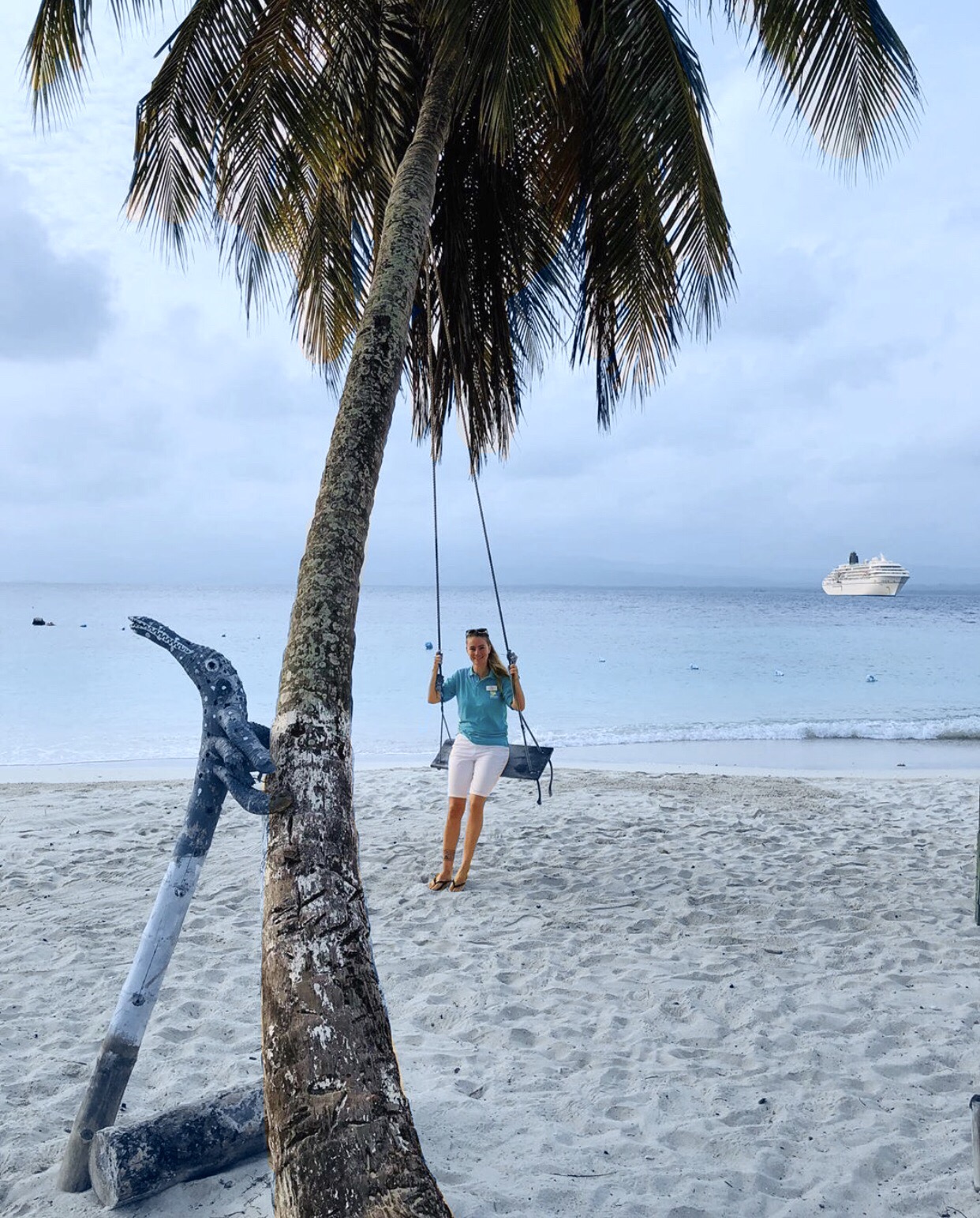 Crewmitglied von Phoenix Reisen am Strand in der Karibik auf Schaukel vor dem Schiff