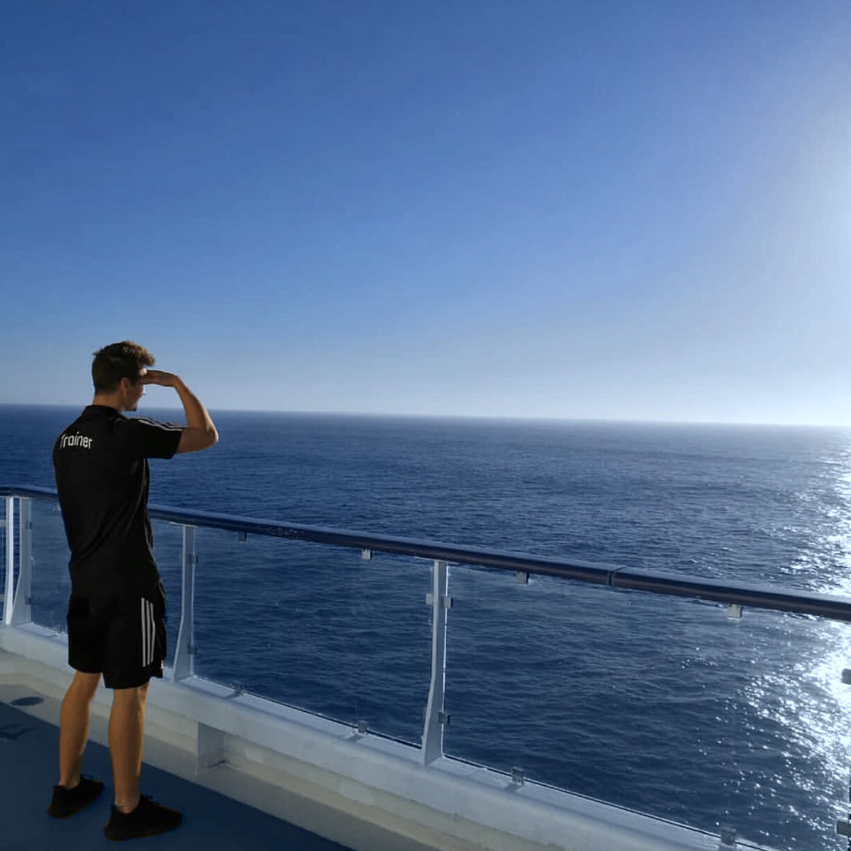 Trainer auf der Mein Schiff auf Deck schaut auf den Horizont auf Pooldeck der Mein Schiff 2