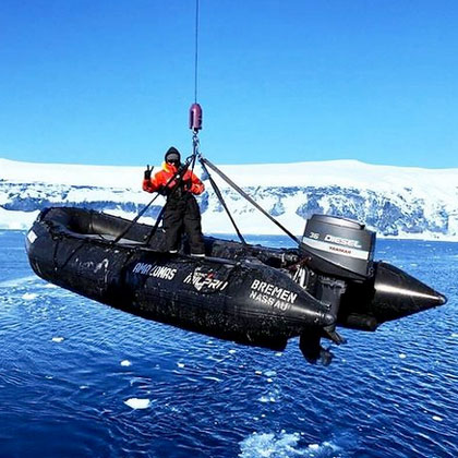 Crewmitglied der MS Bremen von Hapag-Lloyd Cruises wird vor Eisbergen im Zodiac zu Wasser gelassen