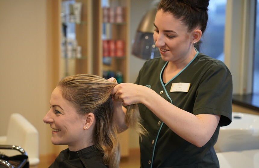 Crew Mitglied lässt sich beim Bord-Friseur im Ocean Spa auf MS AMERA die Haare legen