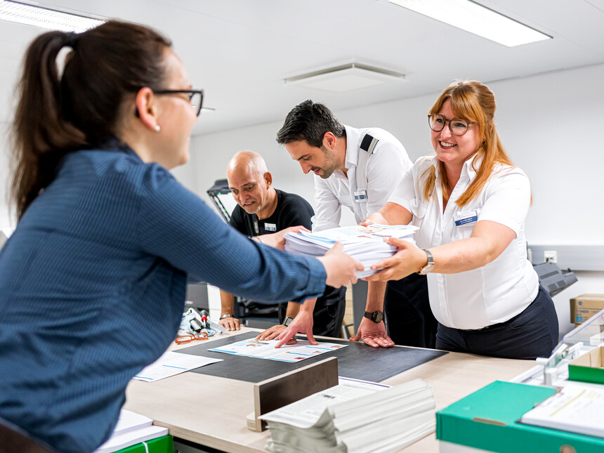 Mediengestalter auf Mein Schiff gibt Printmaterial an Gästeservice