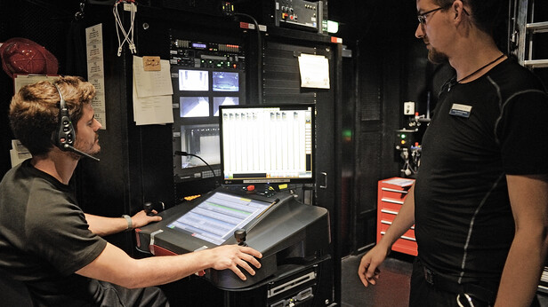 Bühnentechniker sitzen beisammen und bereiten eine Show am Computer vor