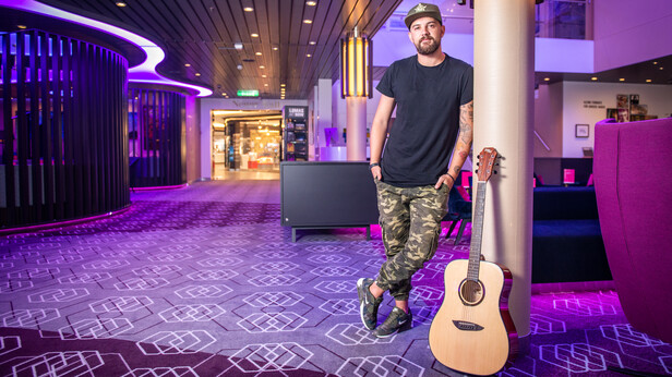 Musiker mit Gitarre in einer Bar an Bord der Mein Schiff