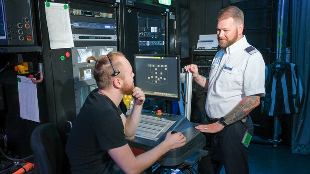 Technischer Leiter erklährt Entertainment-Mitarbeiter etwas im Backstage Bereich