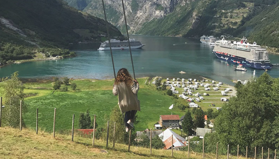 Crew Mitglied schaukelt am Geiranger Fjörd mit Blick auf Mein Schiff