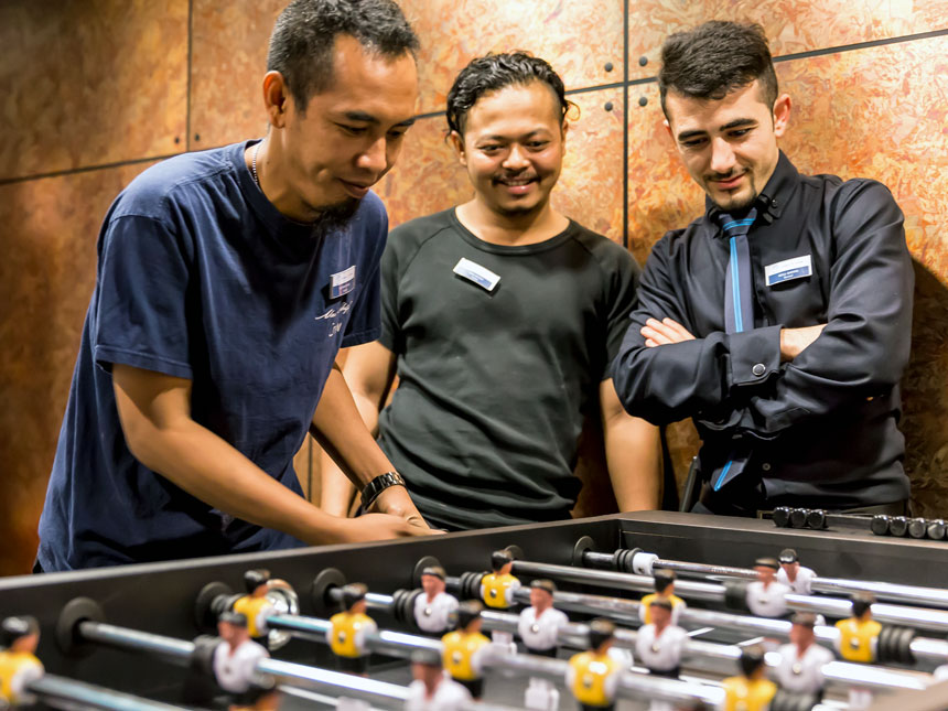 Freizeitbereiche an Bord der Mein Schiff Flotte, Crew-Mitglieder spielen am Tischkicker