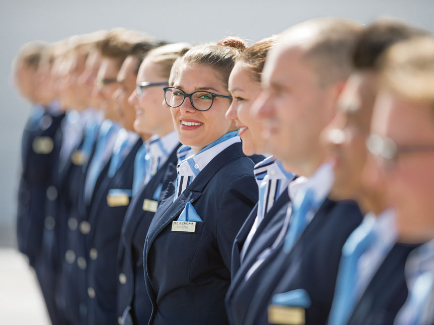 Crew von Hapag-Lloyd Cruises steht spalier, ein Crew Mitglied sieht in Kamera